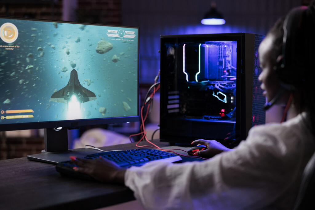 Young happy woman playing shooting video games on pc